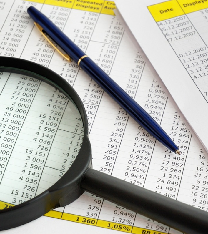 A magnifying glass and a pen on a page of financial figures